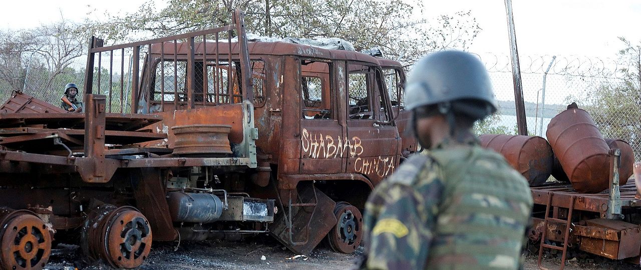 Ein rwandischer Soldat auf Patrouille im Hafen von Mocimboa da Praia am 22. September 2021. Das Graffiti auf dem ausgebrannten Lastwagen ist in Swahili und bedeutet «Shabaab Schlächterei» (Bild: REUTERS/Baz Ratner)